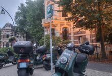 "Parkeervakken in de Stationsstraat gevuld met meerdere Felyx-deelscooters onder een hub-bord voor deelvoertuigen, met monumentale panden op de achtergrond.