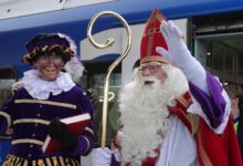 Sinterklaas poseert bij de trein samen met de Hoofdpiet na zijn vertraagde aankomst op station Stadshagen. - Foto © RTV Focus Zwolle