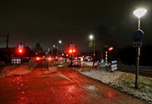 Spoorwegovergang in Zwolle-Zuid blijft gesloten door storing; rood knipperlicht, stilstaand verkeer en nat wegdek in de avond. - Foto © RTV Focus Zwolle