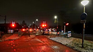 Spoorwegovergang in Zwolle-Zuid blijft gesloten door storing; rood knipperlicht, stilstaand verkeer en nat wegdek in de avond. - Foto © RTV Focus Zwolle