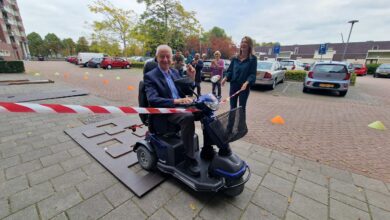 Een bewoner rijdt lachend op een scootmobiel door een symbolisch lint tijdens de feestelijke opening van de scootmobielpool in oktober 2022 - Foto © RTV Focus Zwolle
