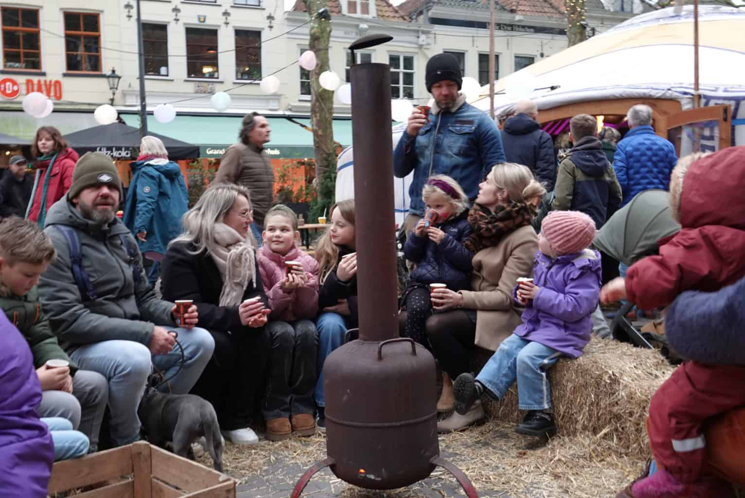 Kinderen en ouders zitten op strobalen bij een vuurkorf tijdens WintersZwolle Festival.