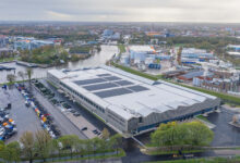 Luchtfoto van Scania’s nieuwe Customer Delivery Center in Zwolle met zonnepanelen en grote truckopstelplaatsen.