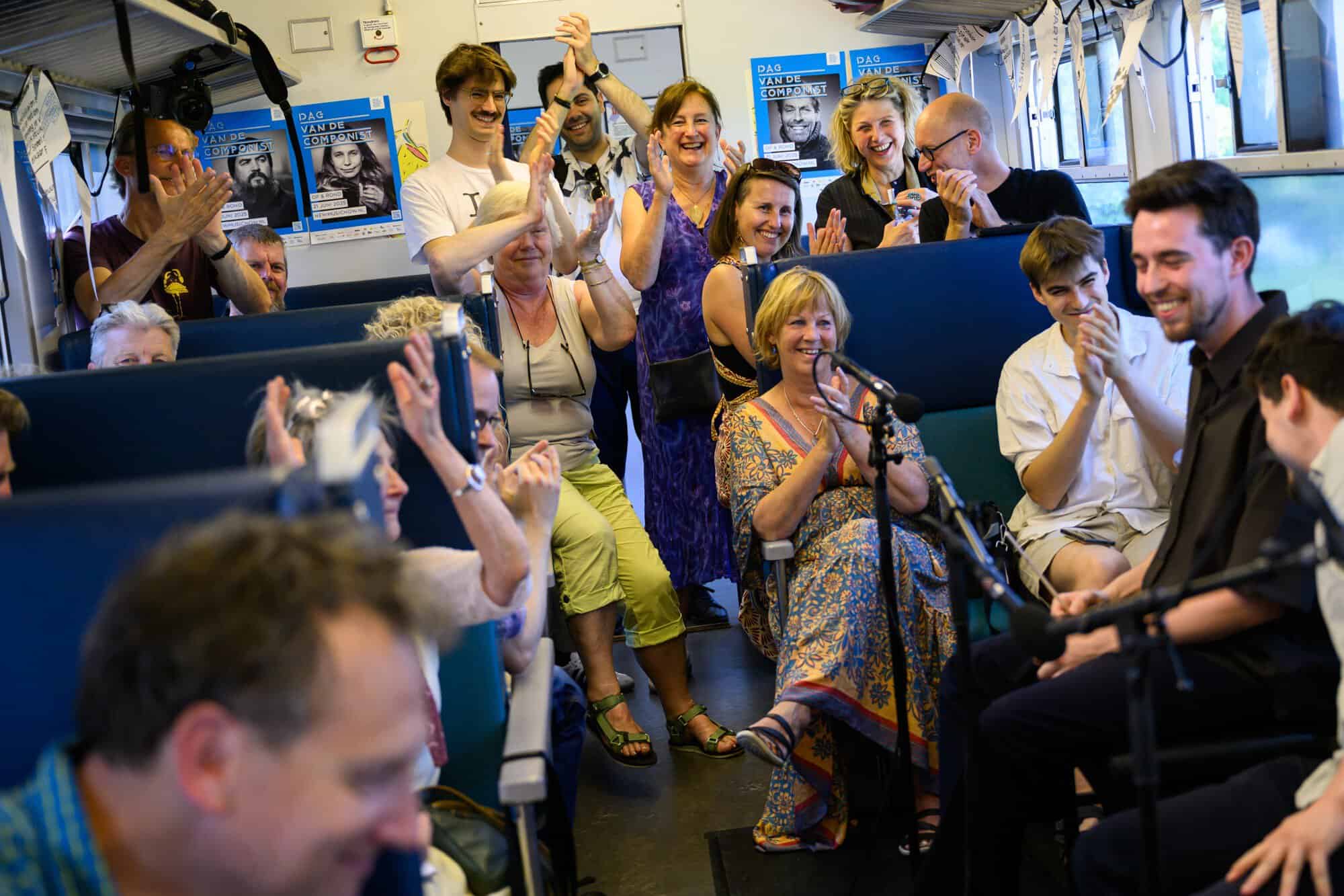 Publiek applaudisseert tijdens een muzikaal optreden in een trein tijdens de Dag van de Componist in Zwolle.