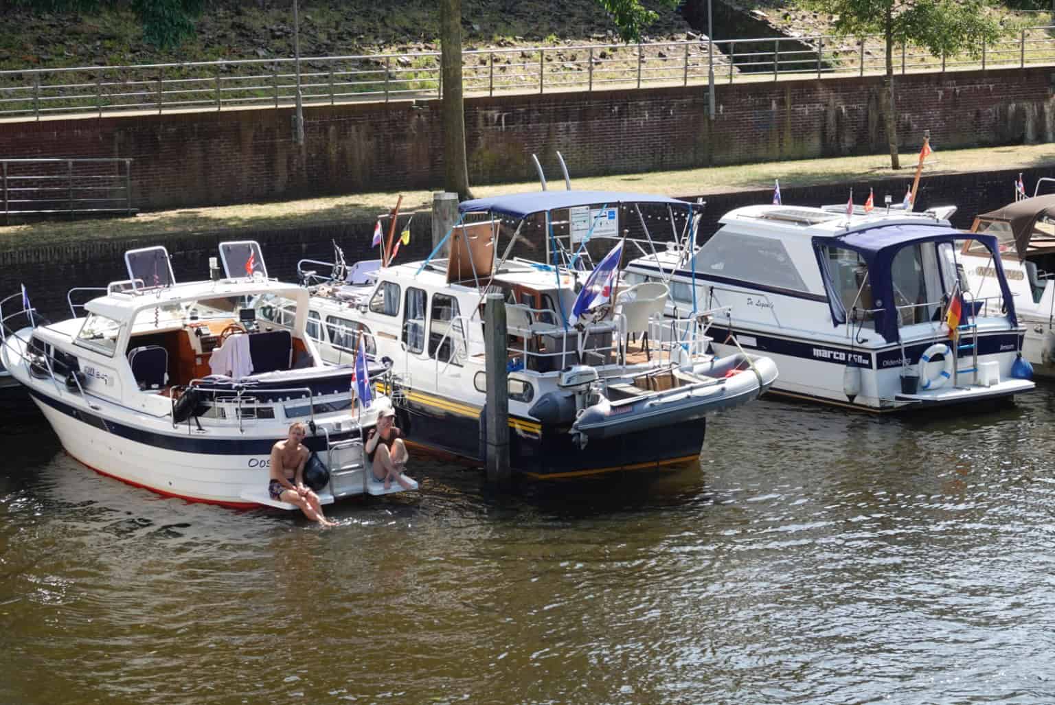 Mensen zoeken verkoeling bij aangemeerde boten in de Thorbeckegracht in Zwolle